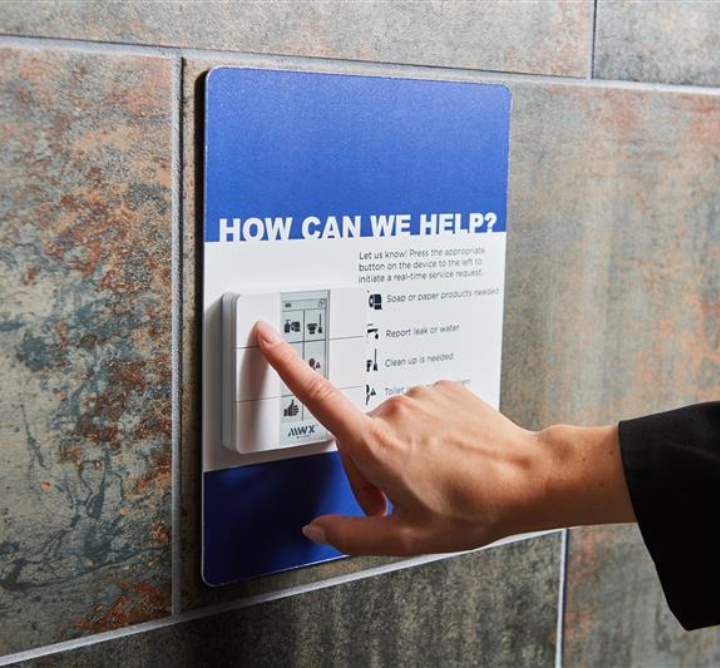 A hand holding up a phone to scan a QR code on the wall for collecting real-time feedback.